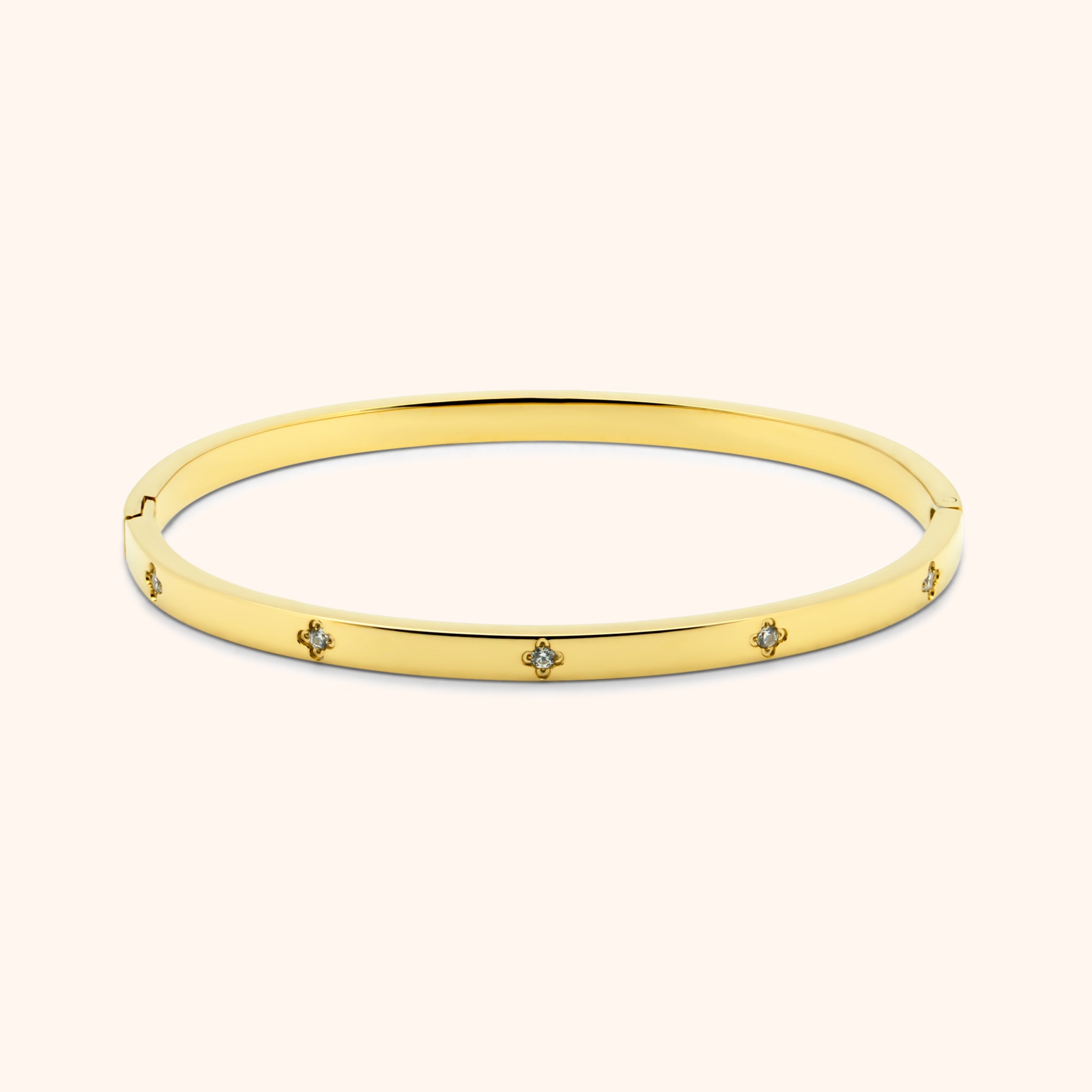 Gold clover bangle bracelet with embedded crystal accents, flat lay